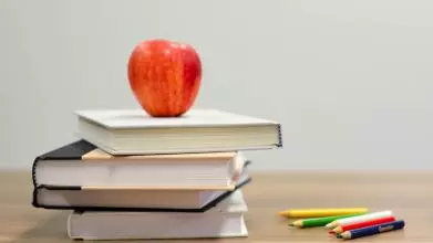 an apple on a pile of books on a desk